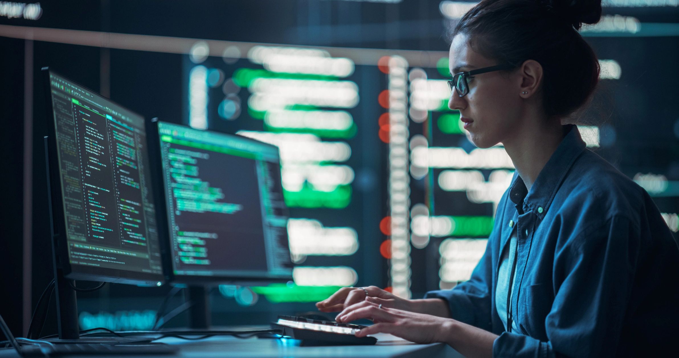 Software developer working with code on multiple screens