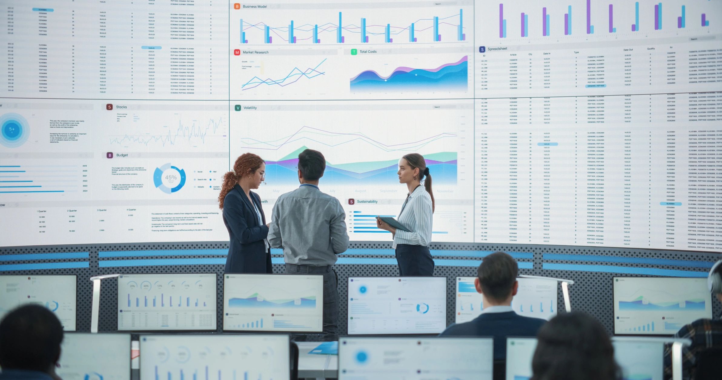 Team collaborating in front of large digital analytics screens